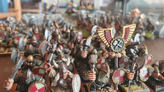 An army of Warhammer The Old World dwarf armies advance behind a banne