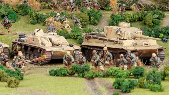 Two model German tanks and infantry on a miniature battlefield, from the WW2 game Bolt Action