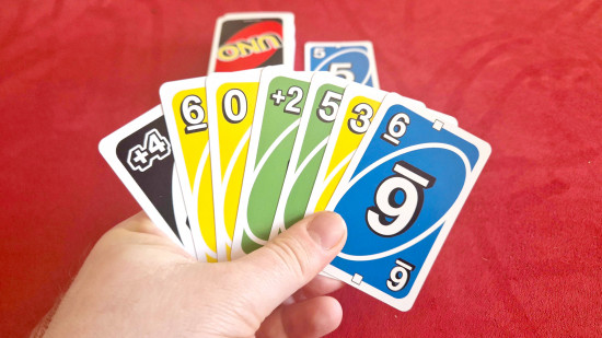 How to play Uno guide - Wargamer photo showing a hand of Uno cards, with a draw pile and discard pile ready to play on the table