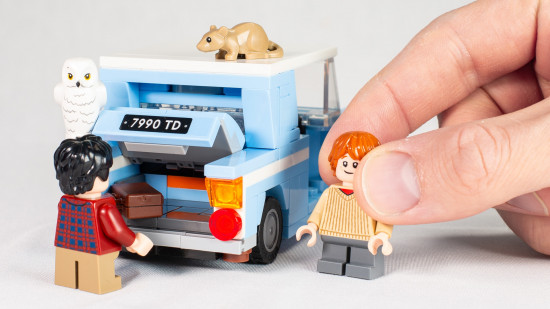 Lego Harry Potter: Flying Ford Anglia review image showing a hand holding Ron, while Harry is posed as if adding something to the boot, with Hedwig and Scabbers on the car.