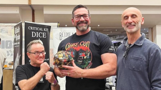 Luke Gygax, son of DnD pioneer Steve Jackson, holds a giant D20 - its maker, Tim Roberts, stands on the left, with charity chair Gary Colman on the right