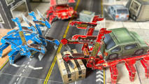 Two junk runners cargo mechs face off against one another with their grabbing claws, one with a car on its back