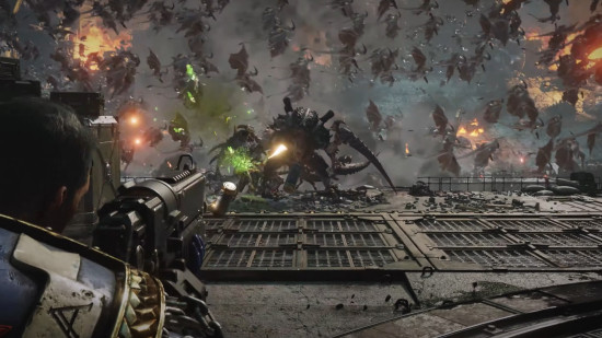 Warhammer 40k Space Marine 2 screenshot - Lieutenant Titus pours fire into a huge Carnifex, a colossal armored alien with bladed limbs