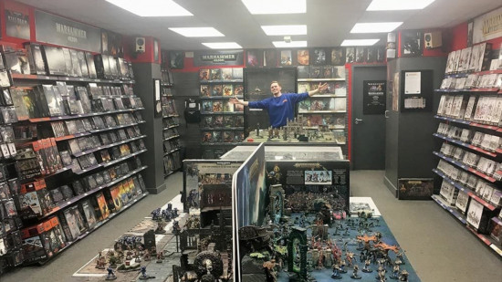 A Warhammer store, with a happy staff member showing off the wide range of products, and gaming tables in the centre