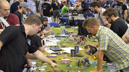 Warmachine tournament at GenCon - players bent over a miniature wargame